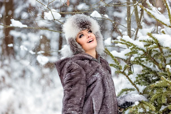Linda chica en gris capa feliz copos de nieve fondo del bosque en invierno — Foto de Stock