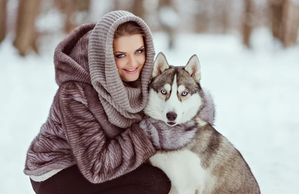 Menina bonito com um cão husky no fundo floresta de inverno, close-up — Fotografia de Stock