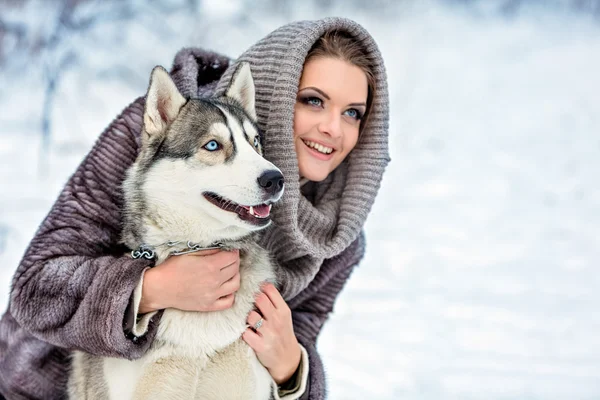 Menina com um cão husky no fundo floresta de inverno, close up — Fotografia de Stock