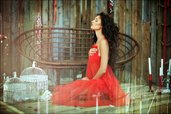 Szexi érzéki nagyon szép göndör lány egy piros ruhás ülő — Stock Fotó