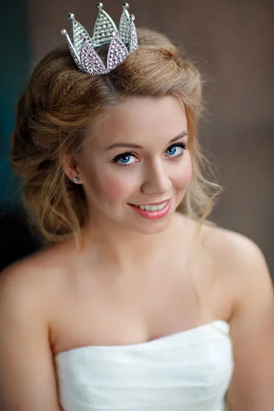 Close-up portrait of a smiling young blonde woman with full lips, wearing a white dress and a crown on his head like a princess — Stock Photo, Image