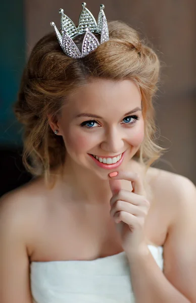 Närbild porträtt av en leende ung blond kvinna med fylliga läppar, klädd i en vit klänning och en krona på huvudet som en prinsessa — Stockfoto