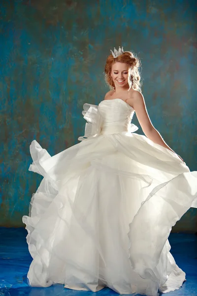 Portrait of a young blonde woman with chic thick hair, dancing and laughing in a white dress and a crown on her head, like a princess, a full-length — Stock Photo, Image