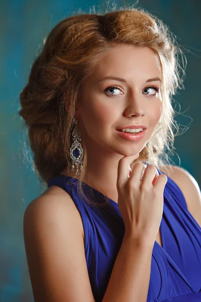 Portret van charmante meisje met dikke blond haar en blauwe ogen in een blauwe jurk jurk in de studio, close-up — Stockfoto