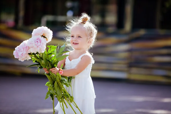 Charmante blond meisje met pioenrozen in de handen van — Stockfoto