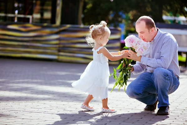 Adorável menina loira dá peônias papai — Fotografia de Stock