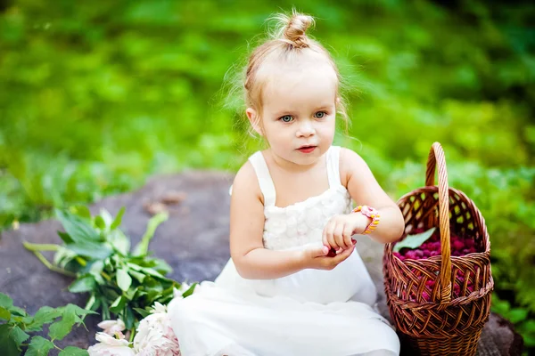 Linda niña rubia comiendo frambuesas de la cesta —  Fotos de Stock