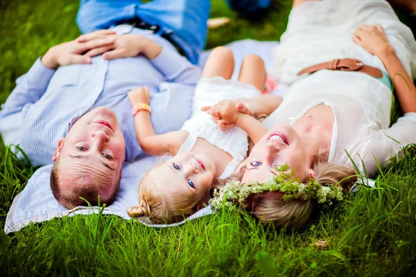 お母さん、お父さんと小さな娘金髪草の上には、一緒に横になっています。 — ストック写真