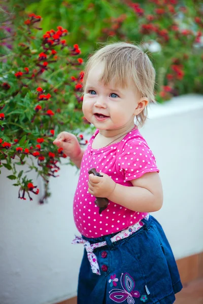 Draguta fetiță într-o bluză roz costă despre floare — Fotografie, imagine de stoc