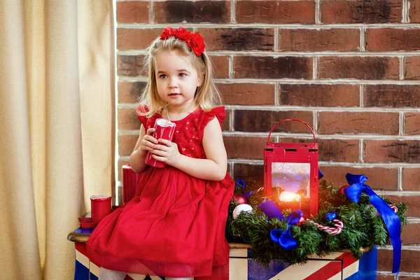 Very cute little baby in a red dress holding a candle — Stockfoto
