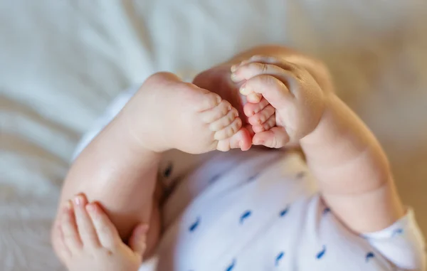 Малюк тримає свої маленькі ноги, крупним планом — стокове фото