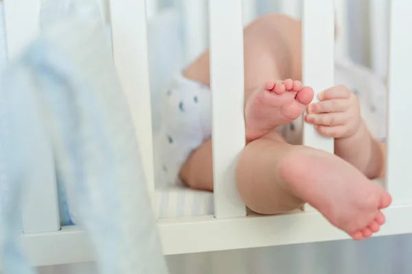 Gambe paffute e maneggiare il bambino per aggrapparsi alle barre del bambino wh — Foto Stock