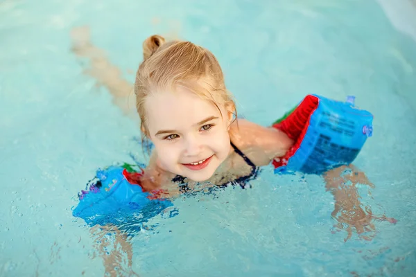 Adorable little blondynka dziewczyna pływanie w basenie z opaski — Zdjęcie stockowe