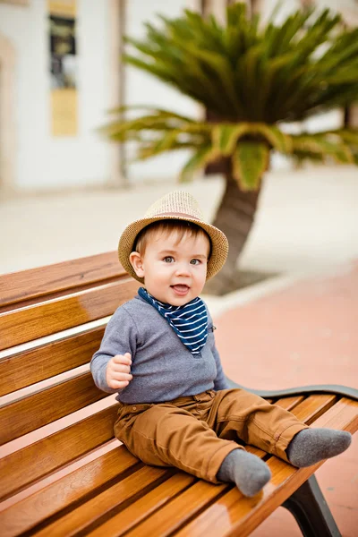 Pequeño niño adorable en un sombrero de paja y pantalones marrones sentado —  Fotos de Stock