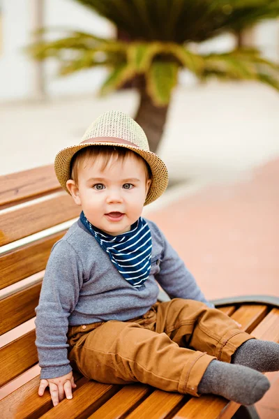 Pequeno menino adorável em um chapéu de palha e calças marrom sentado — Fotografia de Stock