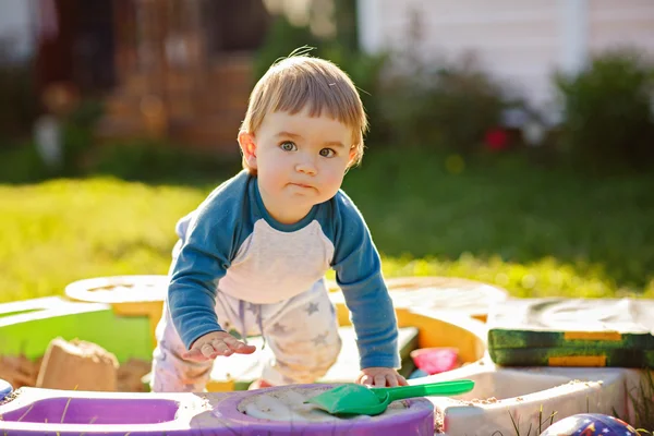 Little chubby toddler boy playing in the sandbox in the summer in Sunny weather — Stock Photo, Image