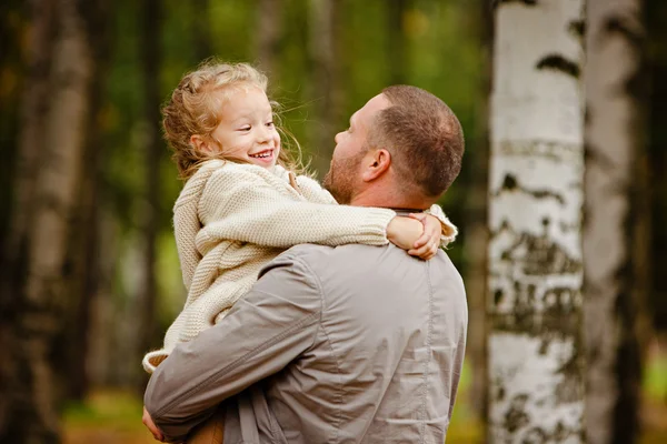 Father holding his daughter in a charming curly beige knitted sw — Stock Photo, Image