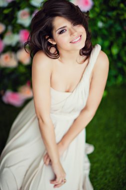 Very beautiful girl brunette in a beige dress smiling and happy