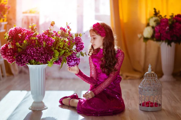 Portret in profiel kroezige meisje in een roze jurk met bloem — Stockfoto