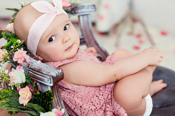 Pequeña niña sonriente de ojos anchos muy lindo en un vestido rosa es i — Foto de Stock