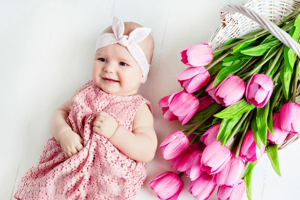 Pequeña muy linda, niña de ojos grandes en un vestido rosa mintiendo — Foto de Stock