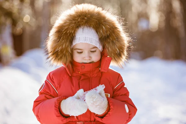 Small very cute girl in a red suit with fur hood holding an icic — Stock Photo, Image