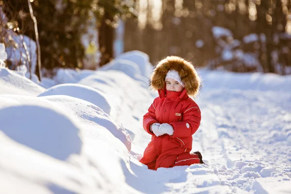 Mały bardzo ładny dziewczyna w czerwonym kolorze z futrem kapturem siedzi na sno — Zdjęcie stockowe