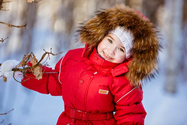 Small very cute girl in a red suit with fur hood standing near a — Stock Photo, Image