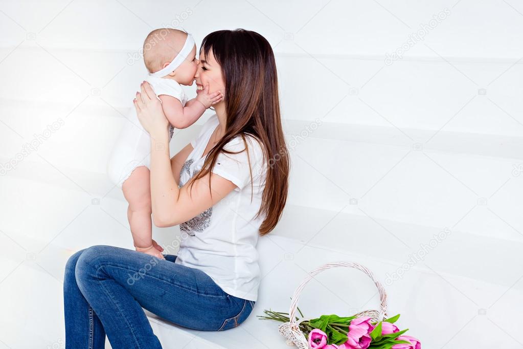 Pequeño sonriente bebé hija muerde su nariz mamá morena en whit — Foto