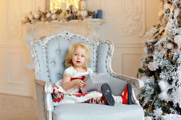 Niña encantadora rubia, sonriente y sentada en una silla — Foto de Stock