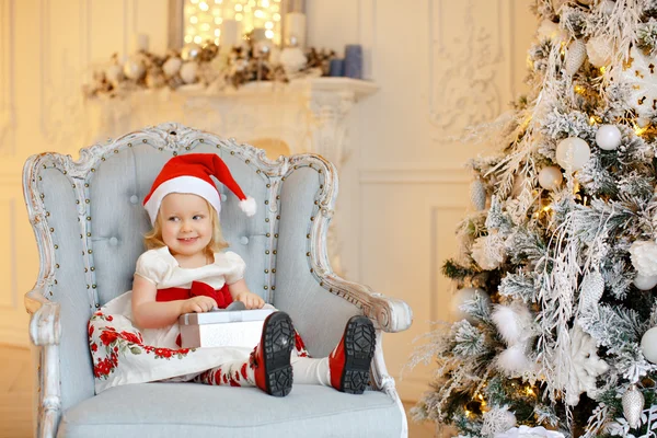 Niña encantadora rubia en un sombrero de santa rojo, sonriente y — Foto de Stock