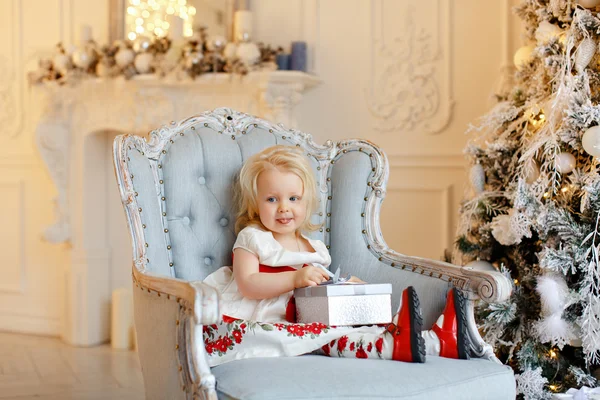 Niña encantadora rubia, sonriente y sentada en una silla — Foto de Stock