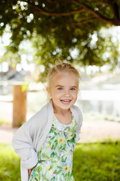 Fetiță blondă în rochie verde zâmbește și râde tare în — Fotografie, imagine de stoc