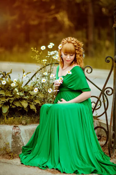 Retrato de uma bela menina grávida de cabelos encaracolados em um dr verde — Fotografia de Stock