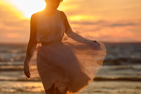 The silhouette of a slim girl in lush pink short skirt, standing