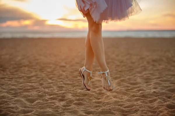 Foto di piedi di donna in una gonna corta lussureggiante rimbalzare sulla sabbia — Foto Stock