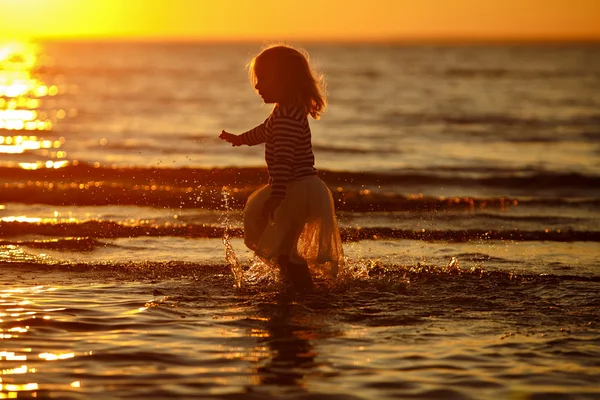 Little girl little girl in a skirt and striped sweater runs thro — Stock Photo, Image