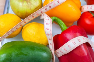 Biber, domates, elma ve limon çatal ile bir ölçekte ve 