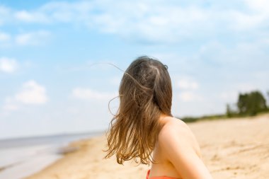 Genç, güzel bir kadın arkadan görünüm bulut ile kumlu bir plaj üzerinde