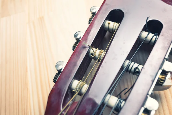 Cabeza y clavijas de una guitarra sobre fondo de madera . —  Fotos de Stock