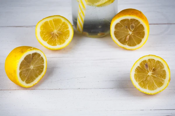 Botella amarilla de limonada con limones y paja . — Foto de Stock