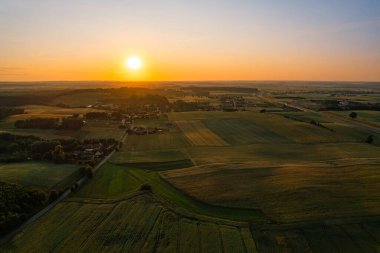 Kırsal kesimde, tarlaları ve ormanları olan altın yaz günbatımının insansız hava aracı görüntüsü