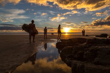 tourists enjoying beautiful sunset in Playa Maderas clipart