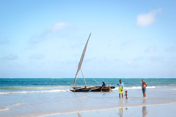 Toeristen wandelen in het strand met lokale boot — Stockfoto