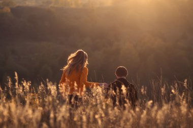 Sonbahar, yaz aylarında açık havada mükemmel bir görünüm ile çok güzel sevimli gün batımı. Genç aile için mükemmel bir seyahat, güzel favori çift. Genç mutlu güzel çift siyah ışık güneş ışığı, mükemmel görünümü ve gün batımı ile açık tepelerde romantik bir tarih var.