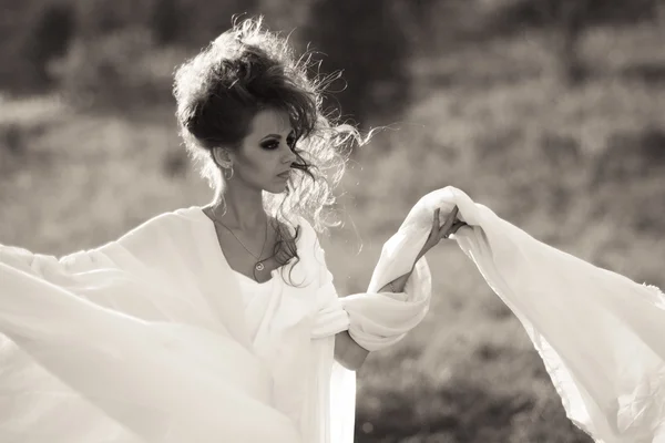 Snorting,stunning,gorgeous,excellent,perfect,beautiful girl,goddess with white dress and white cloth.Female.Professional model with perfect, creative hairstyle and incredibly well-looking white long dress with smokey dark eyes stand on road outdoors. — Stockfoto