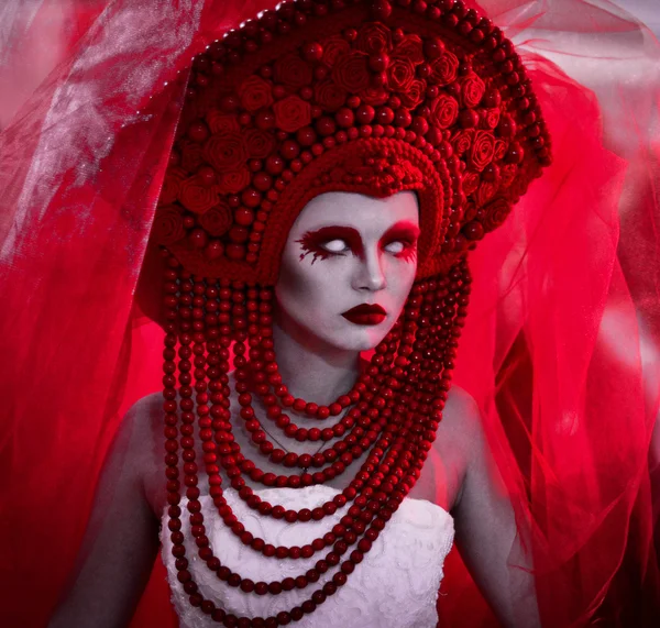 Wedding in red colors, bride in red veil, corona, red makeup and white linces,serious look,white long dress.Creative closeup portrait of fashionable bride,model,girl,woman and strong,serious,angry,dangerous evil look,eyesight on the black background