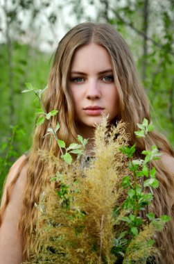 Embodiment.Spring zaman. Harika, mükemmel, güzel, hoş kız uzun, düz, küçük bit kıvırcık saçlı hafif yeşil yaz aylarında açık havada çiçeklerle. Çarpıcı kız, sakin ve ciddi kız ciddi bir yüz, göz, görme ile birçok çiçek buketi ile.