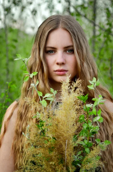 Impresionante, excelente, hermosa, buena chica con el pelo largo, recto, poco rizado ligero con flores al aire libre en la vegetación en verano.Impresionante chica, chica tranquila y seria con cara seria, mira, vista con ramo de muchas flores . — Foto de Stock