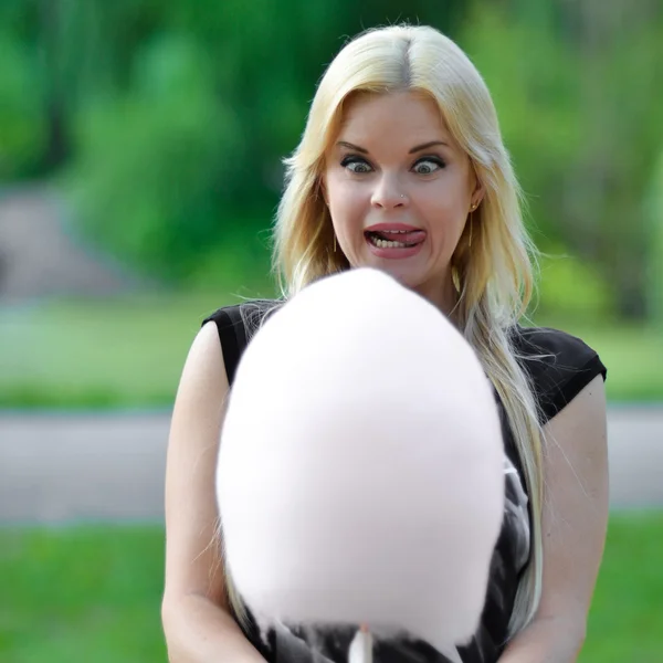 Crazy girl beautiful girl with open mouth,big crazy eyes and protruding tongue look at big cotton candy.Blonde want to eat sweets.Crazy,mad,surprised,amazed blonde girl with crazy eyes look at cotton candy with opened mouth and tounge — Stock Photo, Image